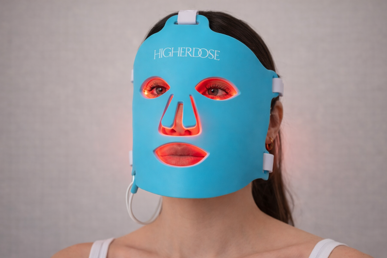 Woman wearing a HigherDOSE red light therapy face mask during an at-home skincare treatment
